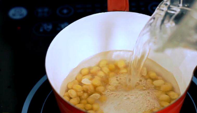 黄豆第一次加水煮至软熟;把水滤掉,第二次重新加入清水煮开.