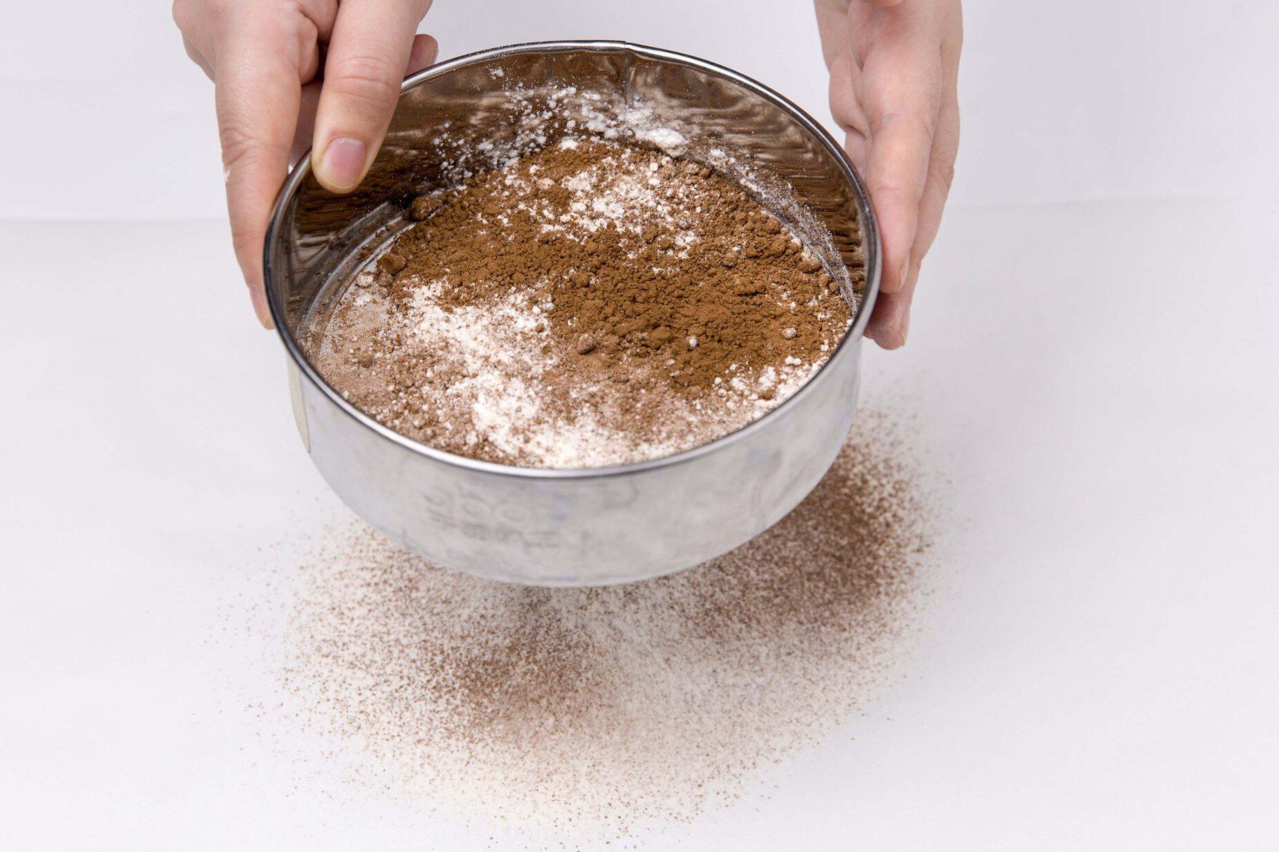 3.低筋面粉70g,可可粉10g过筛后加入牛奶混合物中,翻拌至无干粉.